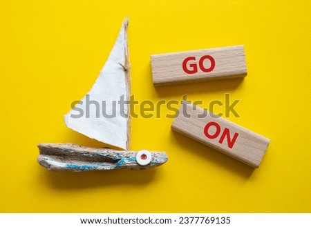 Go on symbol. Wooden blocks with words Go on. Beautiful yellow background with boat. Business and Go on concept. Copy space.