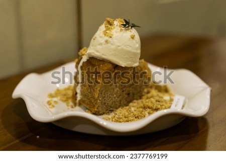 Banana sponge cake with crumbs and vanilla ice cream topping close up photo with bokeh blur background 