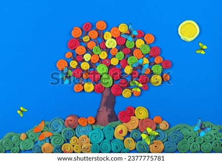 plasticine. plasticine picture. bright colorful autumn tree against the blue sky and morpho butterflies. colorful autumn leaves.