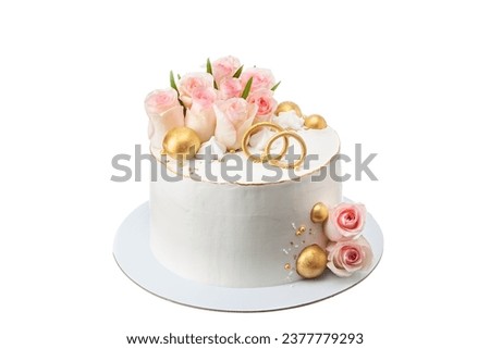 The wedding cake is decorated with flowers and decorative wedding rings with roses and gold decorative balloons. On a white isolated background.