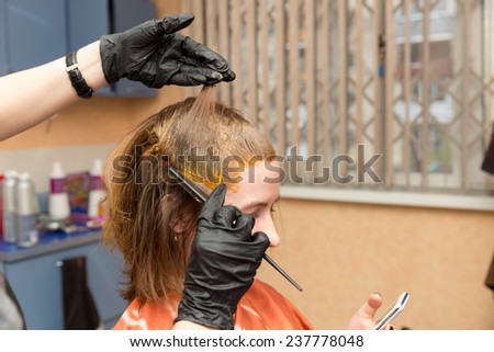 Barber in disposable gloves colors hair red