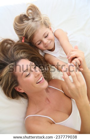 Mother and daughter playing in bed in morning time