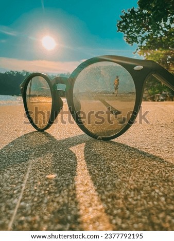 a picture of person standing at the beach using reflection of sunglasses
