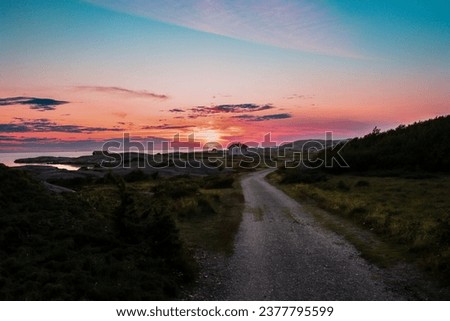 "The sunlit road to the end of the world". A scenic view and the golden sunset and the blue skies over the Skagerrak sea in the background Royalty-Free Stock Photo #2377795599