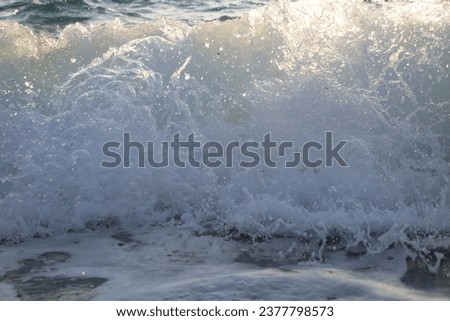 Close up of sea waves at sunset with orange light reflecting from the water