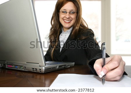 Beautiful thrity something business woman sitting at desk with laptop computer.
