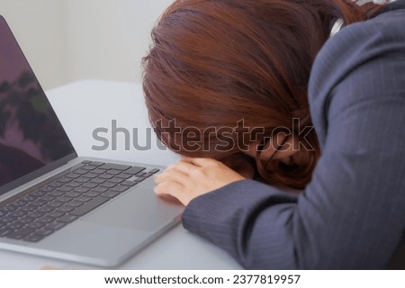A woman with a painful expression at the desk at work