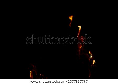Traces of bright golden orange flames against black background with copy space