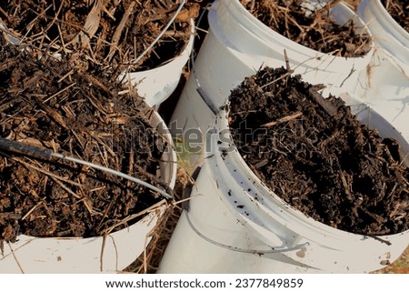 Fertilizer, organic compound or plant substrate stored in white buckets, collected from a compost bin and produced through the composting process. Royalty-Free Stock Photo #2377849859