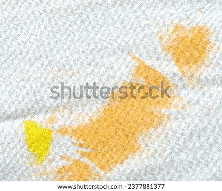 orange and yellow stains on texture of old white textile