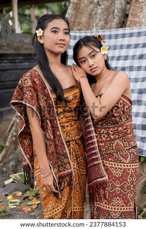 Two women are posing for a picture and one has a flower in her hair