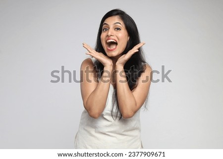 Closeup portrait of Indian woman looking surprised in full of open mouth looks with joyful expression with different facial expressions hands movements isolated over grey studio background.