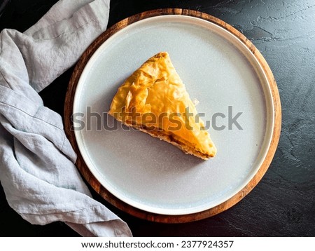 Filo pastry pie with one slice on a plate, feta Greek pie top view, mediterranean food picture, tiropita