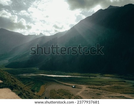 Hunza's Enchanted Vista: Gilgit-Baltistan Pakistan - Sep, 2021: Sun-kissed peaks emerald fields and a glistening lake nature's masterpiece unfolds spellbinding tapestry of Hunza's breathtaking beauty Royalty-Free Stock Photo #2377937681