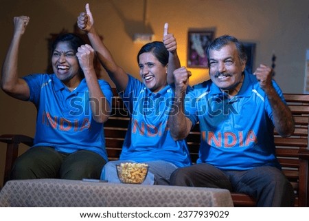 excited family celebrating victory of Cricket Team in Indian jersey, watching on tv or television at home - concept of World cup match, championship and Sports fans or audience