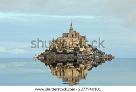 Reflected on the water at high tide of the Hill with the ancient abbey of Mont Saint Michel in Normandy in Northern France and the blue sky Royalty-Free Stock Photo #2377940101