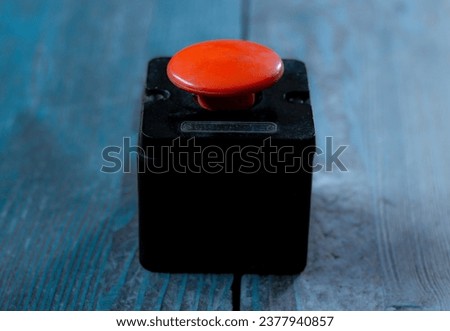 The concept of the threat of nuclear war. Red button on cold blue wooden background