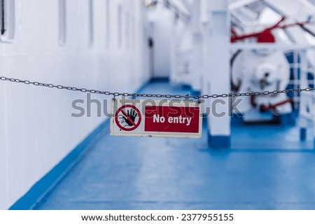 No entry warning sign in red colour. It is attached with a chain on the outside of a ship.