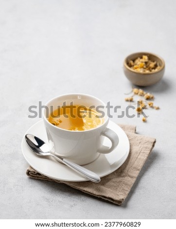 Chamomile herbal tea with lemon in a white cup on a light background with dry flowers. The concept of a healthy detox drink for health and sleep. Free space for text. Royalty-Free Stock Photo #2377960829