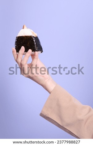 The Asian woman holding onigiri on purplr background.