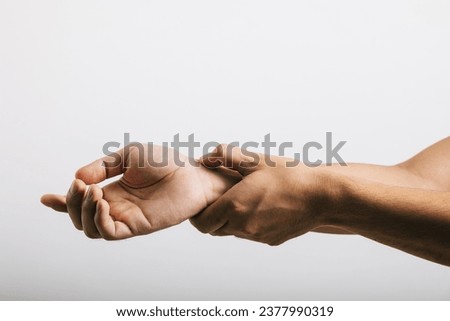 A sad Asian man, expressing discomfort due to wrist pain, possibly caused by carpal tunnel syndrome. Studio shot isolated on white, highlighting health care and medical issues.
