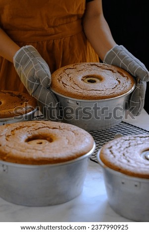 Hand in frame, chiffon cake in pan Royalty-Free Stock Photo #2377990925