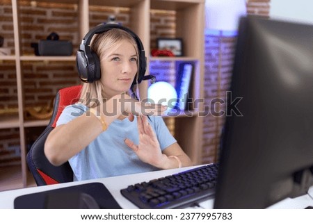 Young caucasian woman playing video games wearing headphones doing time out gesture with hands, frustrated and serious face  Royalty-Free Stock Photo #2377995783