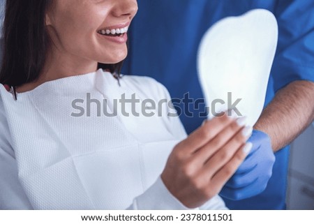 Beautiful young woman is sitting in dentist's chair and smiling, having her teeth treated