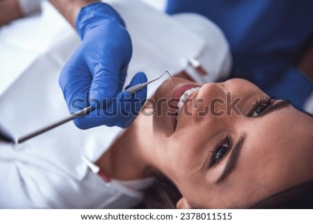 Beautiful young woman is sitting in dentist's chair while doctor is examining her teeth Royalty-Free Stock Photo #2378011515