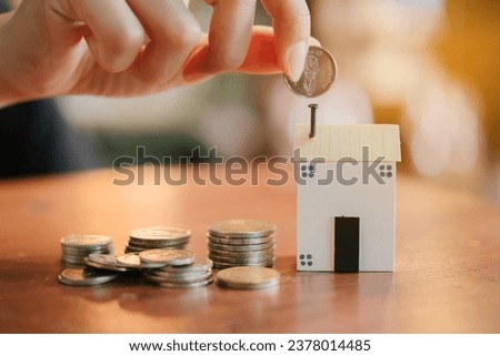 Hand hold coin put to small wooden house. Real estate concept. New house concept.