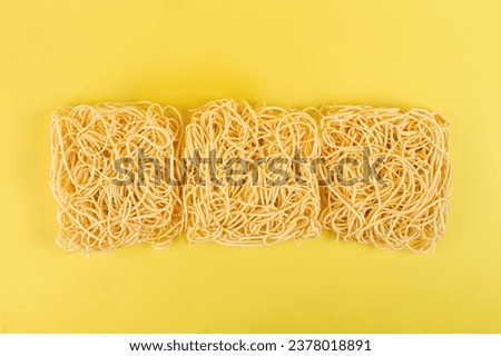 Dry egg noodles on a yellow background.