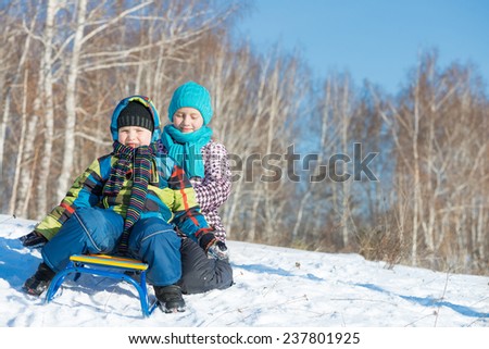 Two cute kids riding sled and having fun