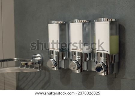 Three dispensers for cosmetics in the bathroom of a hotel room. Interior details of a chain hotel. Taking care of hotel guests. Royalty-Free Stock Photo #2378026825