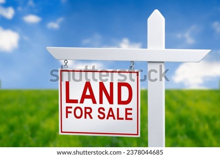 Beautiful green field and blue sky with LAND FOR SALE sign