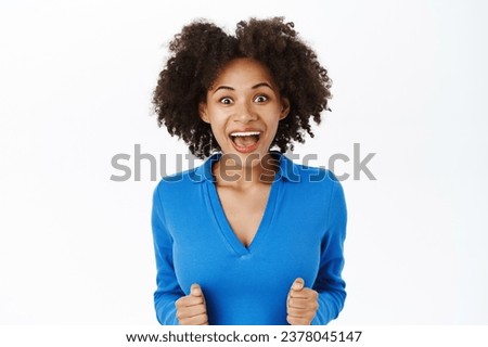 Achievement and goals. Young woman winning, celebrating victory, looking enthusiastic, stands with clenched fists and looks amazed, thrilled with great news, white background.