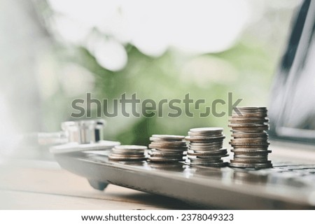 close up stack of coin, stethoscope and computer on table, saving and manage money for healthy, life insurance business technology, economic crisis risk and problem concept