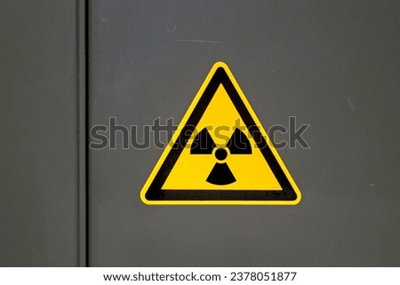 Yellow caution sign on a metal door warning about "Ionizing radiation".