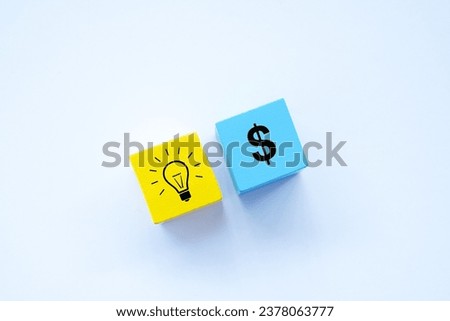 Top view coloured wooden block with light bulb sign as a symbol of idea and dollar sign. Business and finance concept