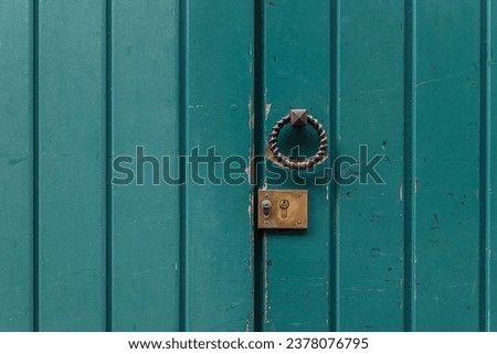 Close-up front view of old green painted rough wooden door with black steel doorknob. 
