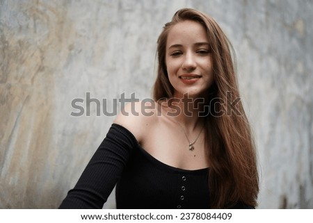 Head shot portrait smart confident smiling millennial woman standing against wall. Attractive young teenager girl freelancer looking at camera, posing for photo.