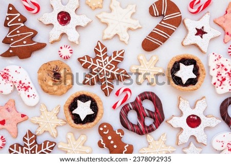 Christmas baking background with an assortment of cookies and sweet treats. Top down view on a white marble background. Holiday baking concept.