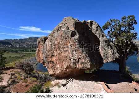 Large boulder with lake in background at Escalante Petrified Forest in Utah Royalty-Free Stock Photo #2378100591