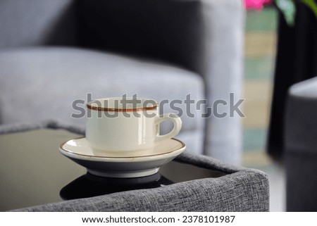A white cup of coffee on a minimalistic table in a serene minimal living room backdrop.
