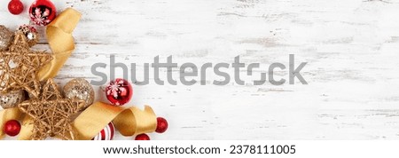 Christmas corner border of gold and red ribbon and ornaments. Above view on a white wood banner background. Copy space.