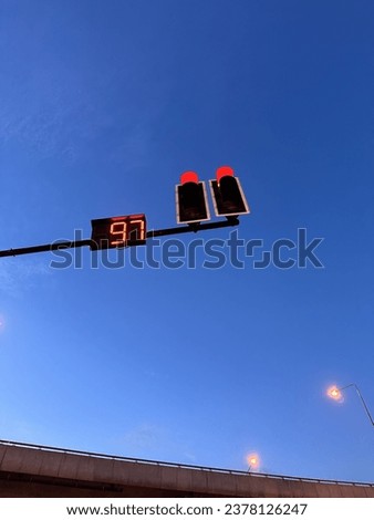 Red traffic lights with countdown numbers under the sky.