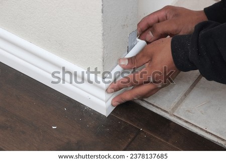 Male hands installing baseboards at the corner of a room Royalty-Free Stock Photo #2378137685
