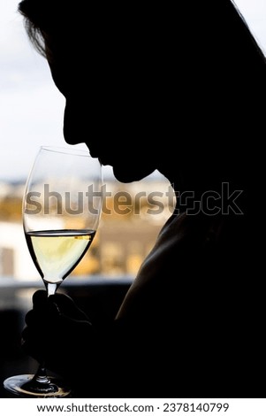Woman drinking white wine, silhouette with glass
