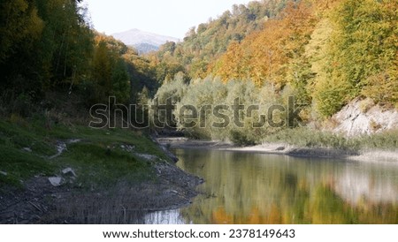 Lakeview in Măneciu, Romania. Autumn picture with lake reflection in the Carpathian Mountains. River flow in a sunny day.