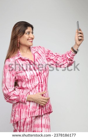 Indian woman taking selfie with smartphone isolated on grey background