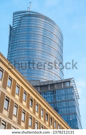 Two buildings from different eras: a modern glass skyscraper and an old low office building Royalty-Free Stock Photo #2378212131